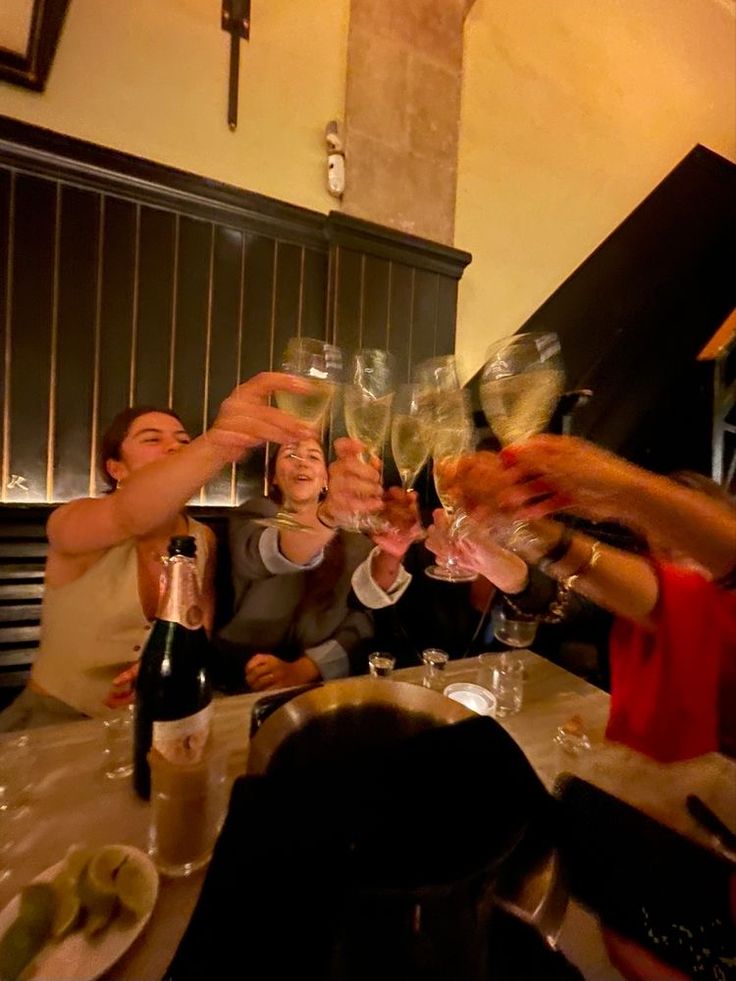 a group of people toasting with wine glasses in front of them on a table