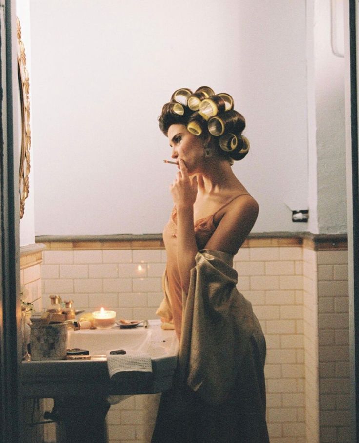 a woman with curls on her head standing in front of a sink