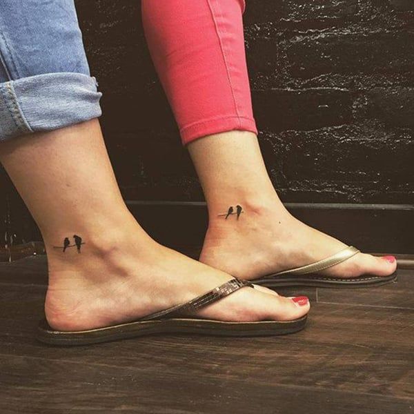 two people with matching tattoos on their feet, one is wearing sandals and the other has red