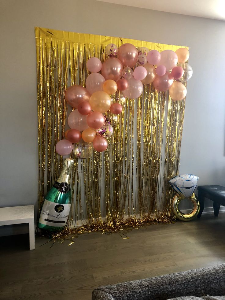 balloons and streamers are hanging from the wall in front of a party backdrop with champagne