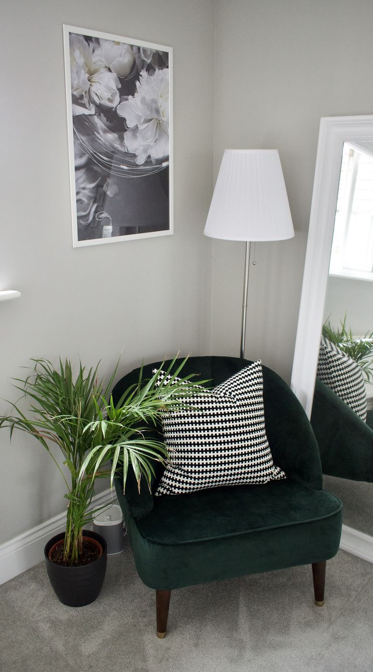 a green chair sitting in front of a mirror next to a potted plant