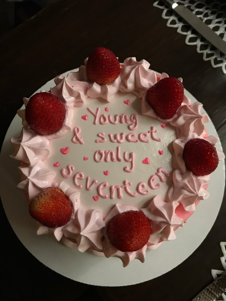 a white cake with pink frosting and strawberries on top that says young & sweet only served