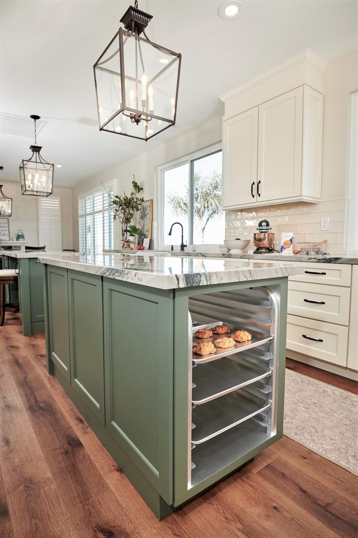 a kitchen with an island that has donuts in it and lights hanging from the ceiling