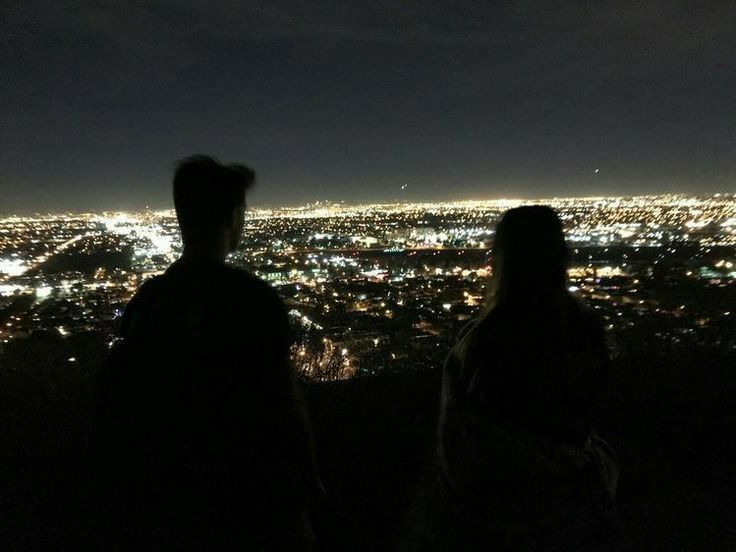 two people looking out over the city at night