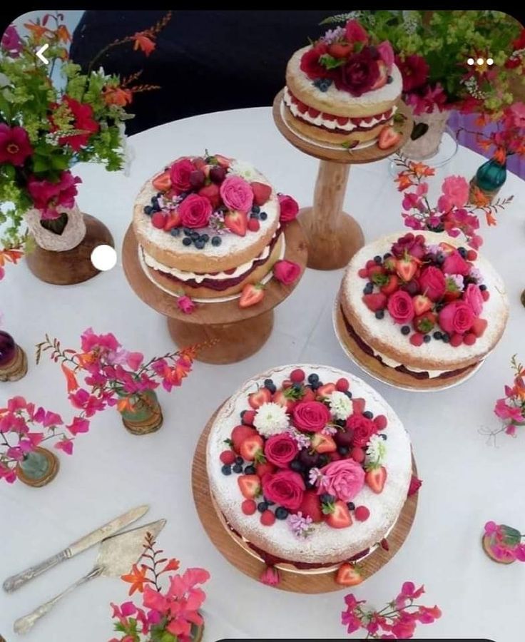 a table topped with three cakes covered in frosting and colorful flowers on top of each cake