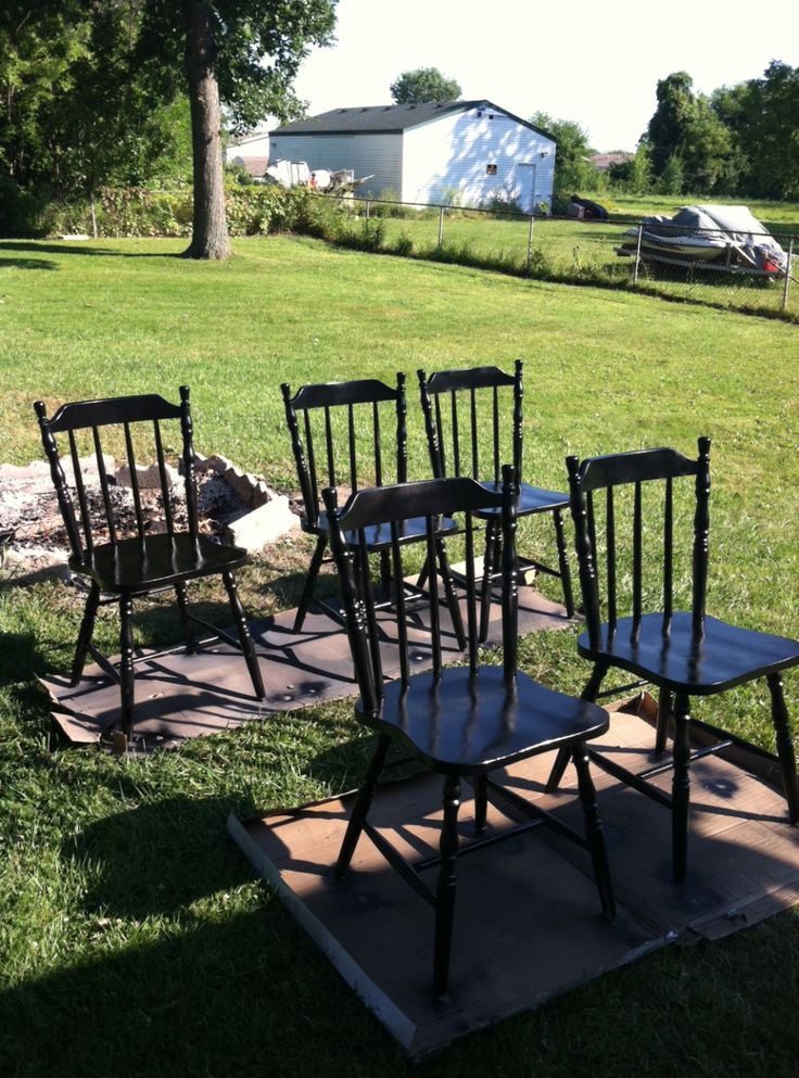 four wooden chairs sitting on top of a patch of grass