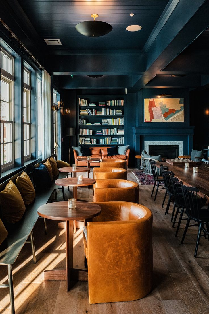 an empty restaurant with tables, chairs and bookshelves in front of large windows