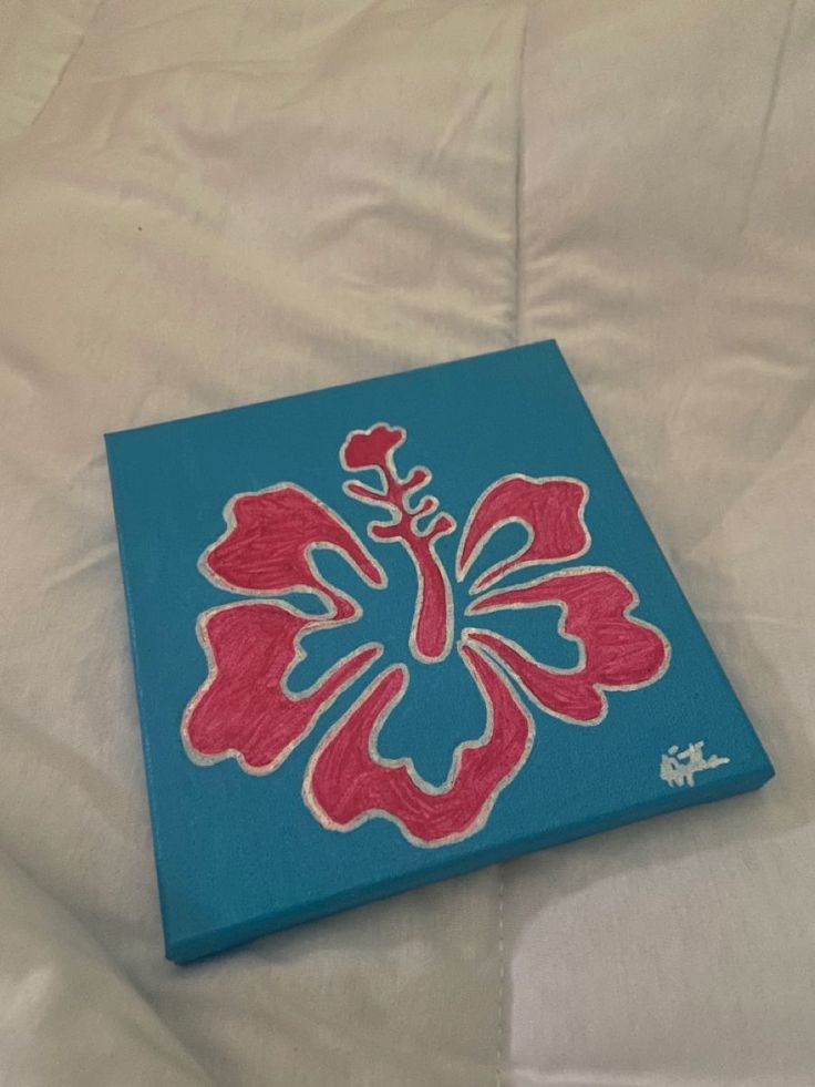 a blue and red painted canvas on a white sheet with a flower in the center