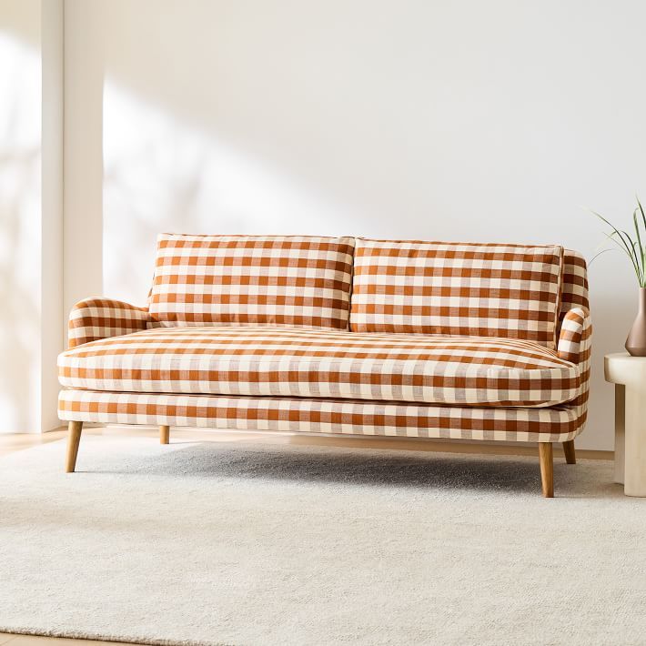 an orange and white checkered couch sitting on top of a rug