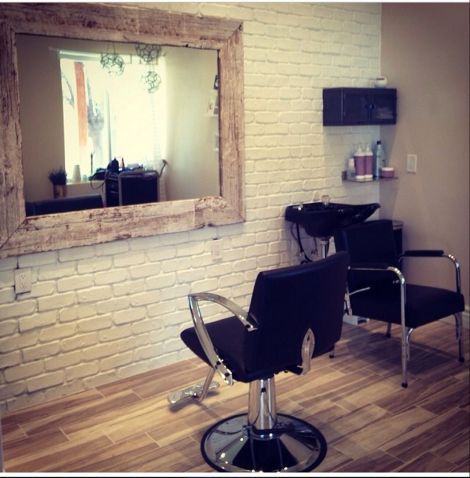 a salon chair sitting in front of a brick wall with a mirror on the wall