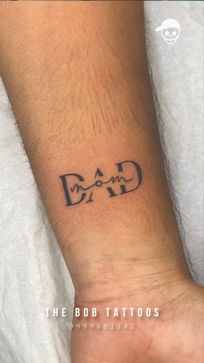 a man's wrist tattoo with the word dad on it, in black ink