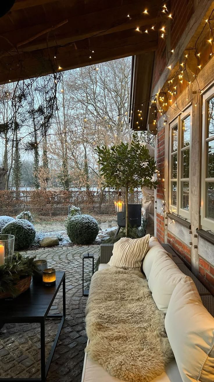 an outdoor living room with lights strung from the ceiling