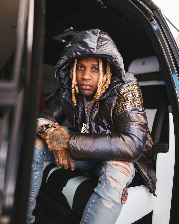 a man with dreadlocks sitting in the back of a car wearing a black jacket