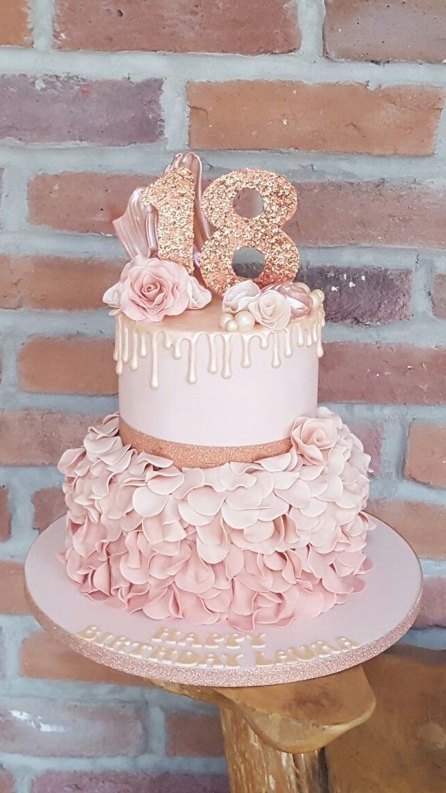 a three tiered cake with pink flowers and the number twenty on top is sitting on a wooden stand