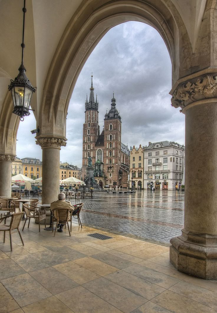 an archway with tables and chairs in front of it on a rainy day at the old town square