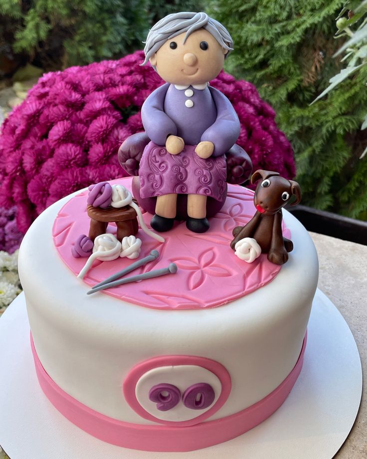 a cake decorated with an older woman sitting on top of it