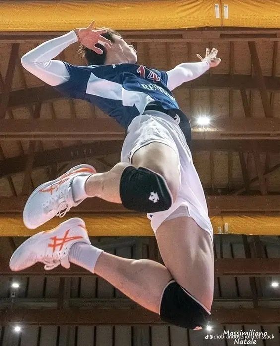 a man jumping up in the air to hit a volleyball ball with his racket