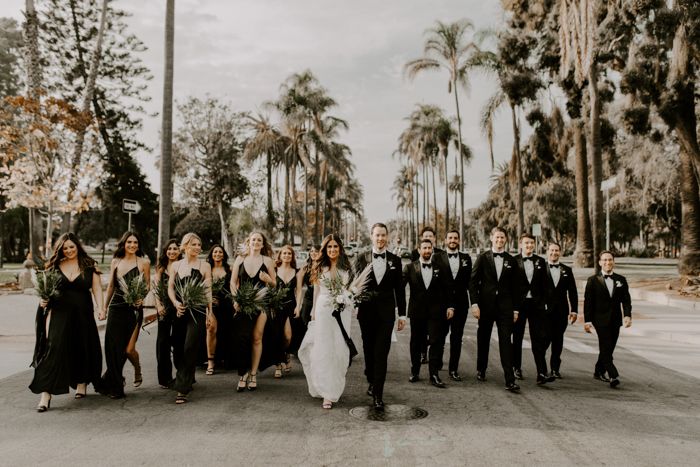 a group of people standing next to each other in front of palm trees and buildings