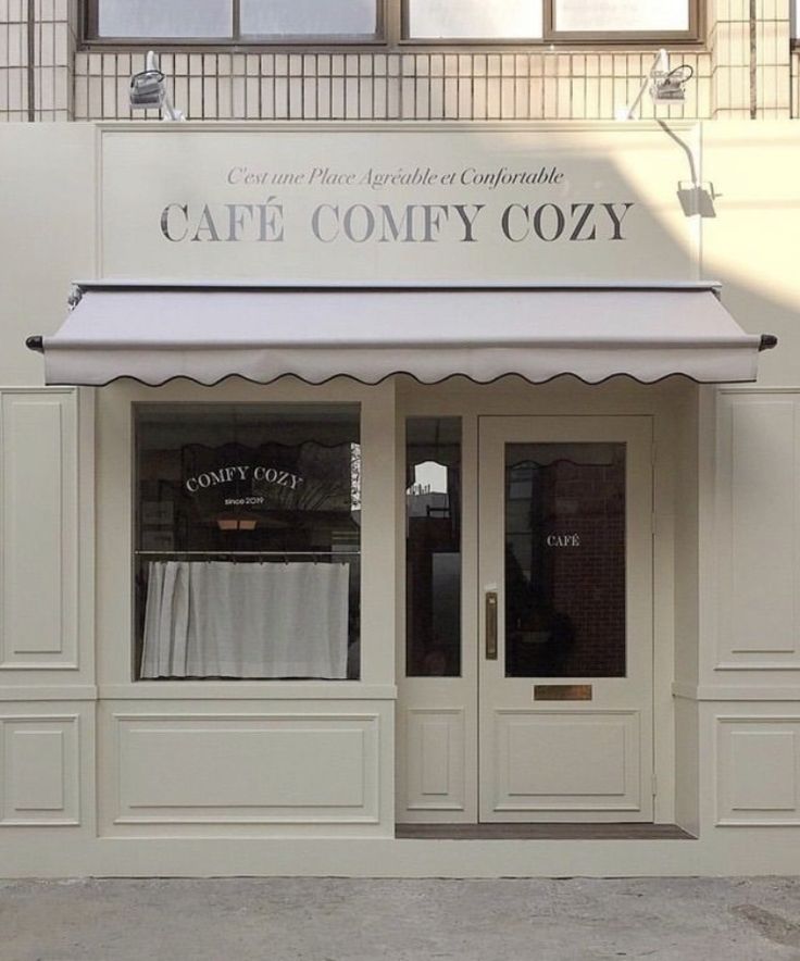 the front entrance to cafe comfy cozy with white awnings and black trim