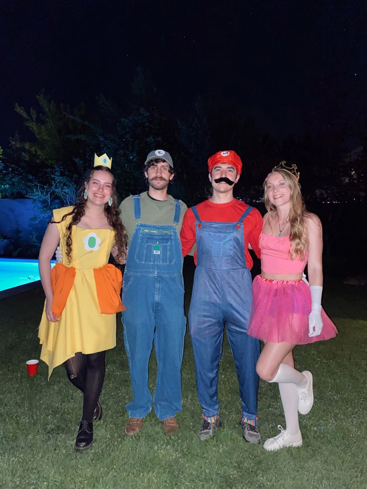 three people dressed up in costumes standing next to each other on the grass at night