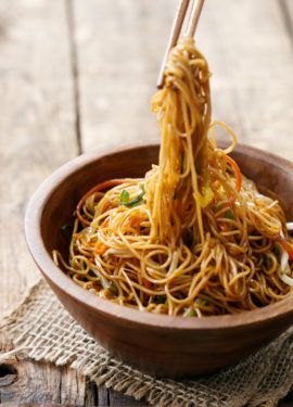 a wooden bowl filled with noodles and chopsticks