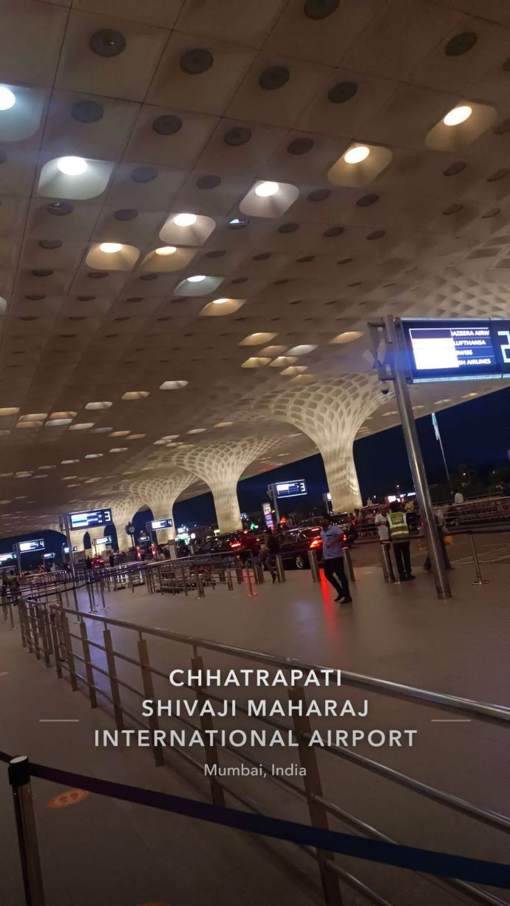 an airport terminal with people walking through the area and lights on the ceiling above them