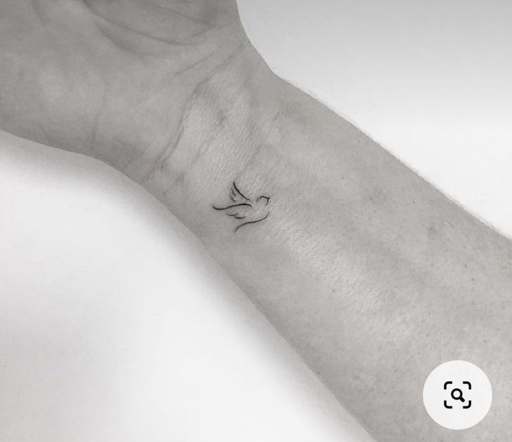 a person's arm with a small bird tattoo on the left side of their wrist