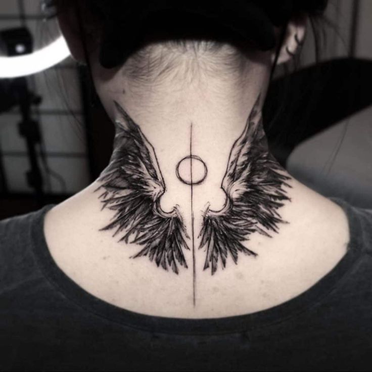 the back of a woman's neck with an angel wing tattoo