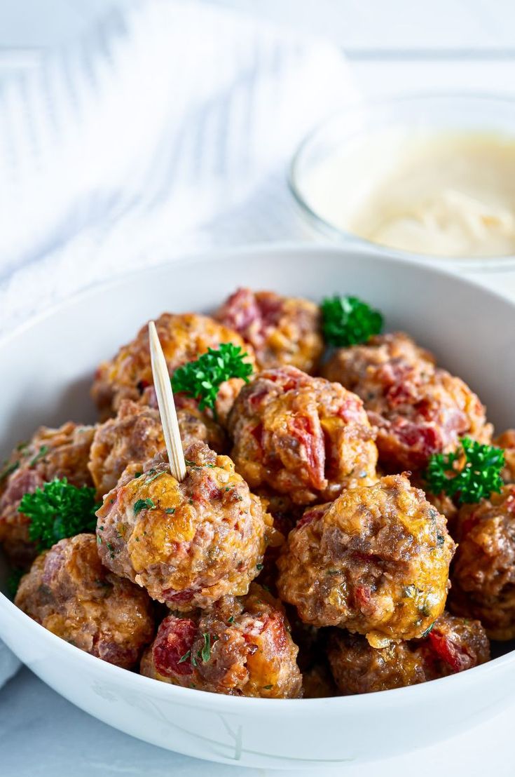 a white bowl filled with meatballs and garnished with parsley