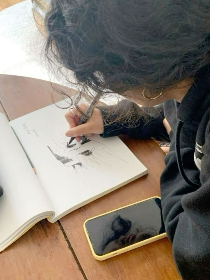 a person sitting at a table with a book and cell phone in front of them