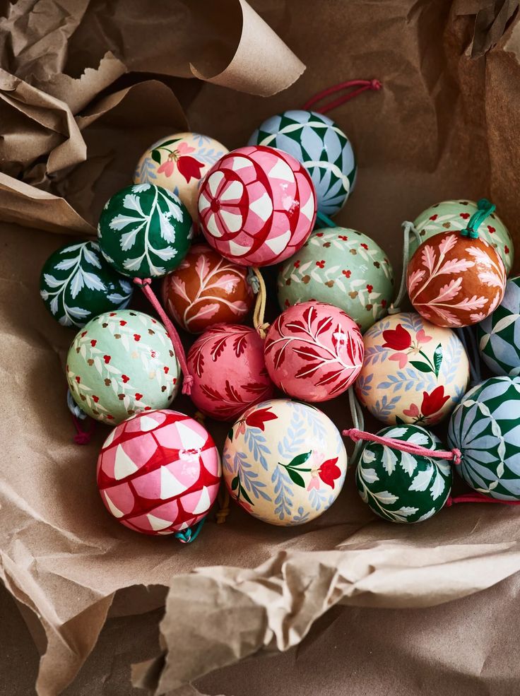 a pile of colorful painted eggs sitting on top of brown paper