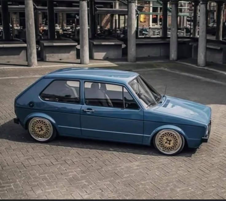 an old blue car parked in front of a building