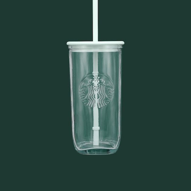 a starbucks cup with a straw in it on a green background and the lid is open