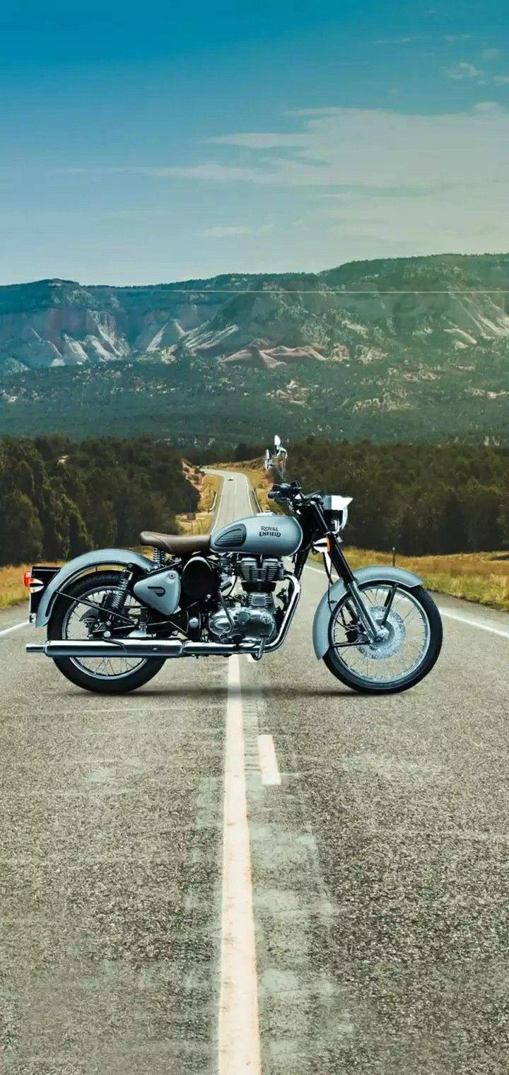 the motorcycle is parked on the side of the road in front of the mountain range