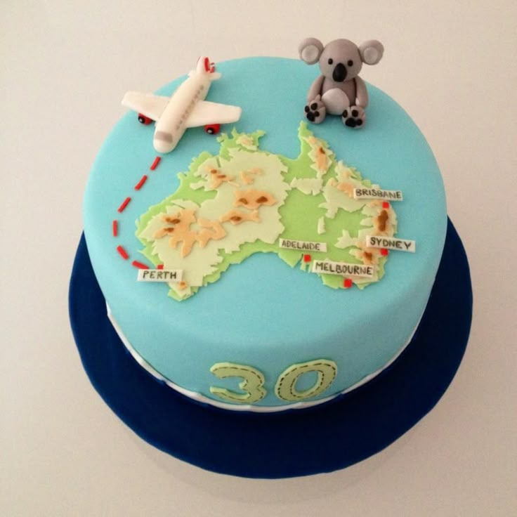 a birthday cake decorated with an australian map and a toy koala bear on top