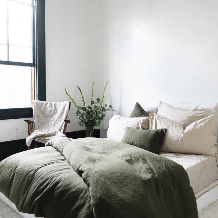 a large bed sitting in a bedroom next to a window with plants on top of it