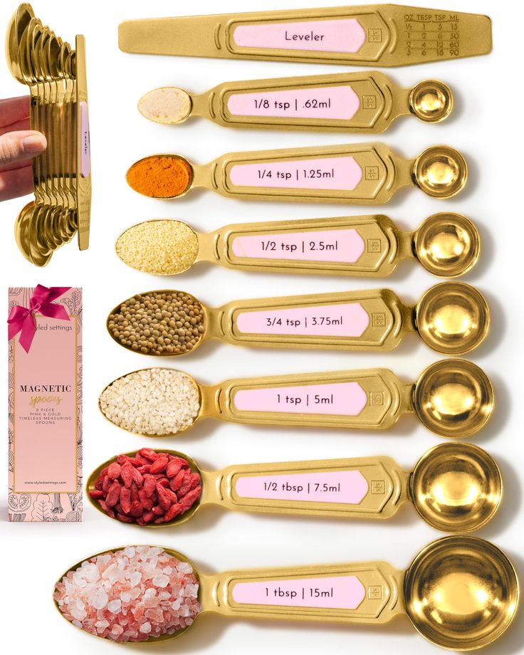 gold measuring spoons with pink labels on them next to other measuring spoons and spices