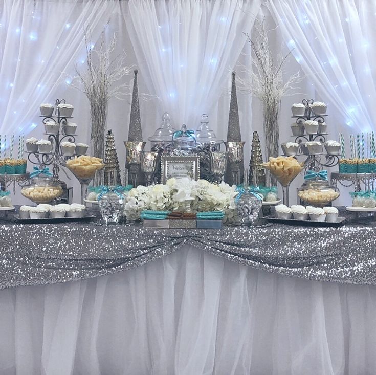 a table topped with lots of desserts next to a white drape covered wall