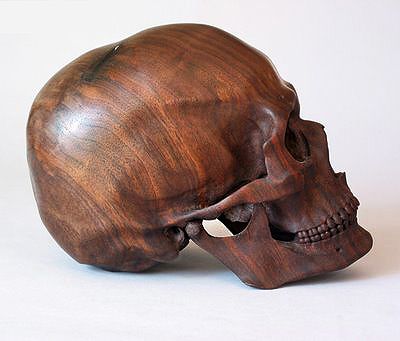 a carved wooden skull on a white background