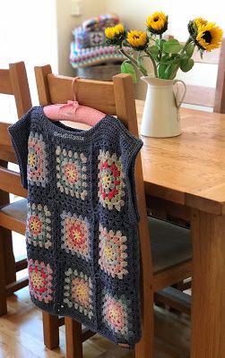 a crocheted sweater hanging from a wooden table