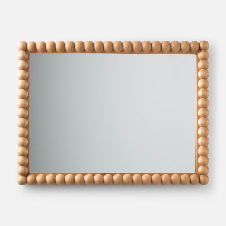 a wooden frame mirror with beading around it