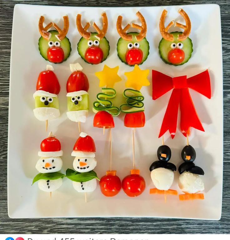 an assortment of food on a white plate with red bows and green vegetables in the shape of santa hats