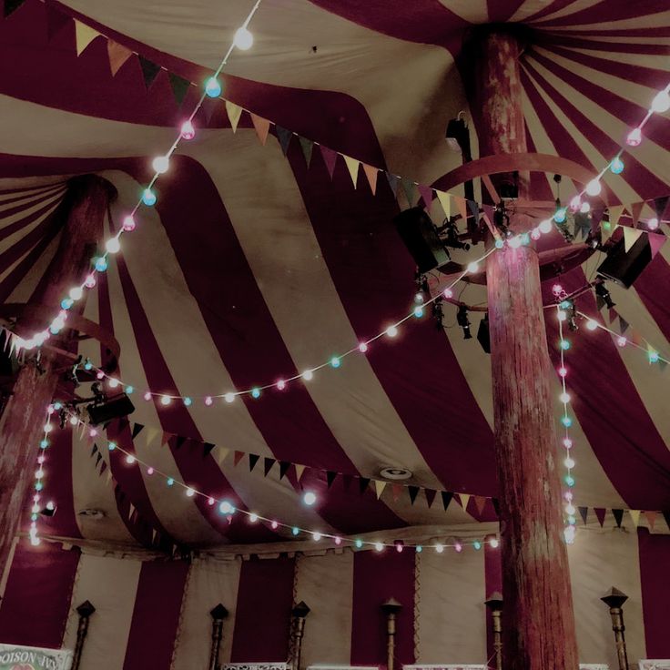 the inside of a large tent with lights strung from it's ceiling and poles