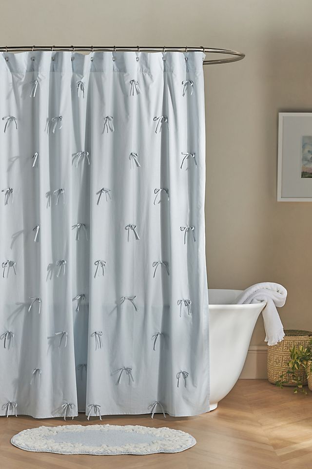 a white bath tub sitting next to a shower curtain with birds on it in a bathroom