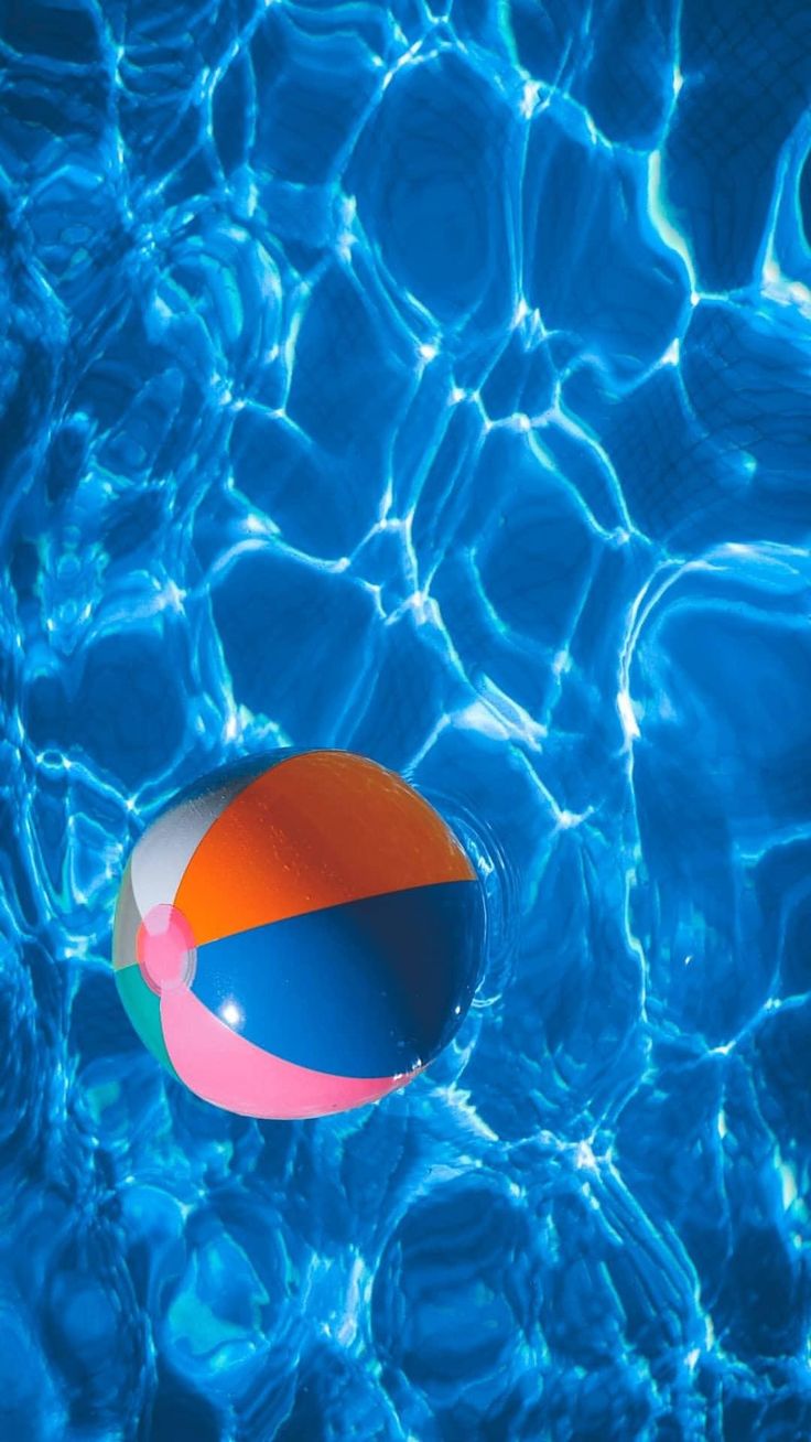 an orange and blue beach ball floating on top of the water in a swimming pool