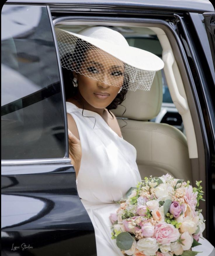 a woman sitting in the back of a car holding a bouquet