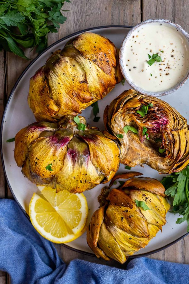 some artichokes are on a plate next to a bowl of ranch dressing