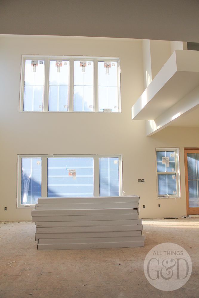 an empty room with three windows and four benches in the foreground, all white