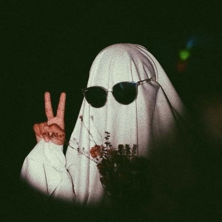 a person wearing sunglasses and a nun costume making the peace sign with their fingers in front of them