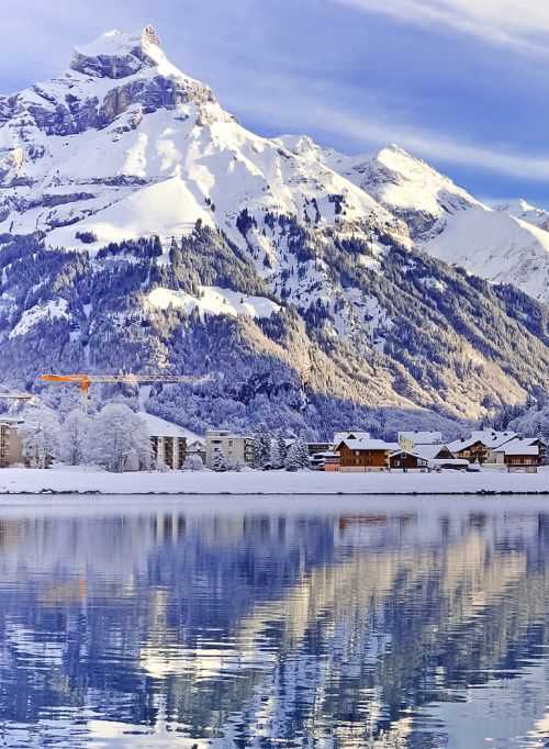 the mountains are covered with snow and reflecting in the water